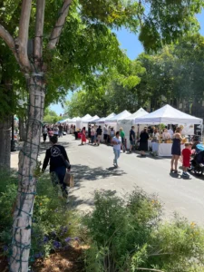 A group of people walking down the street near tents.