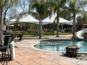 A pool with an umbrella tent in the background.