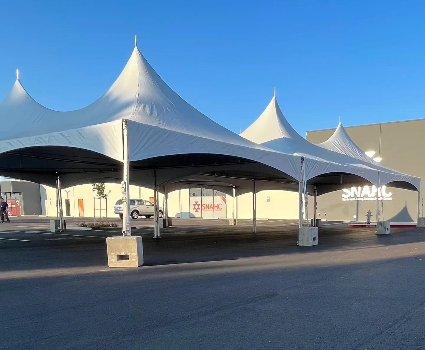 A large white tent is in the middle of a parking lot.