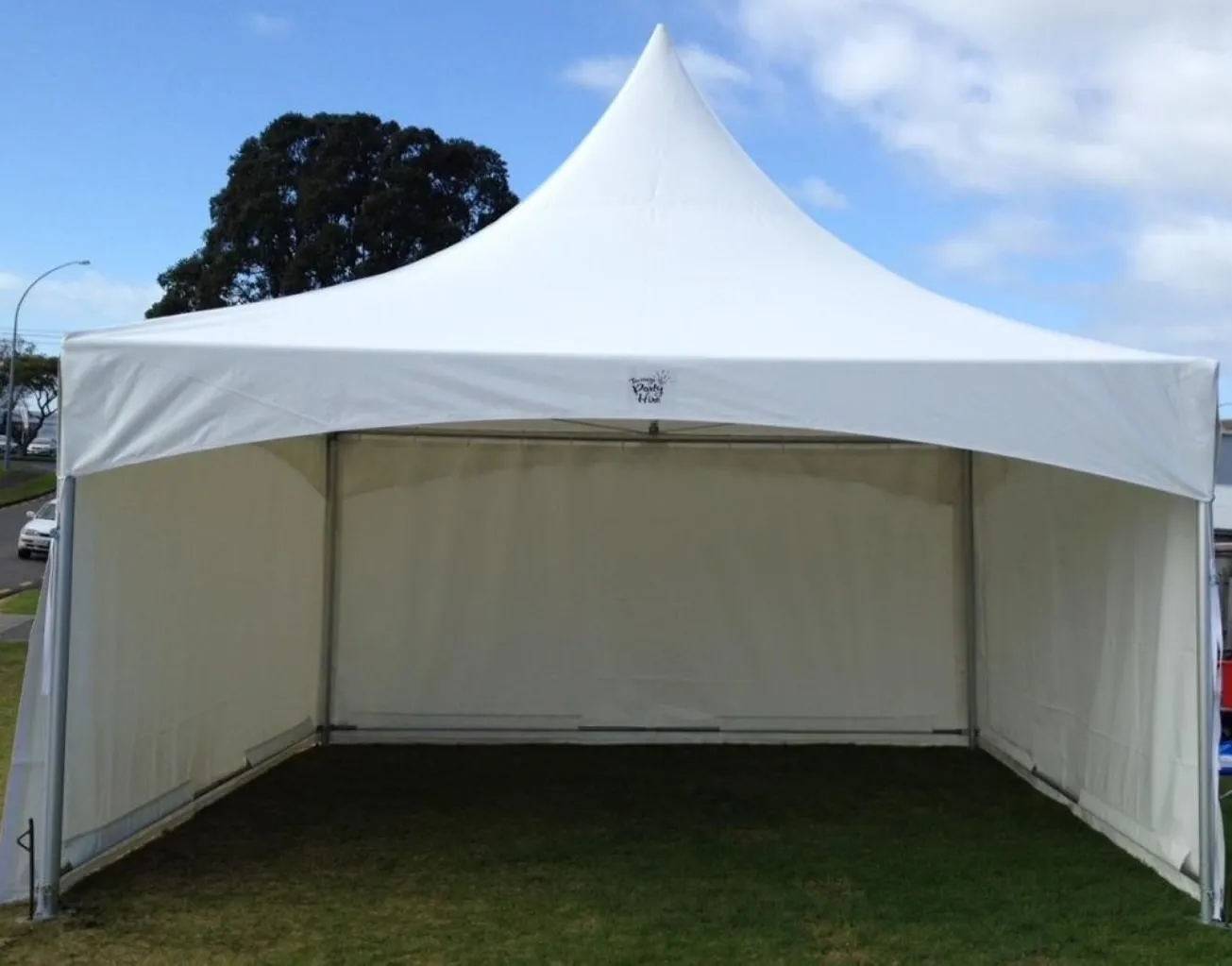 A white tent is in the grass near some trees.