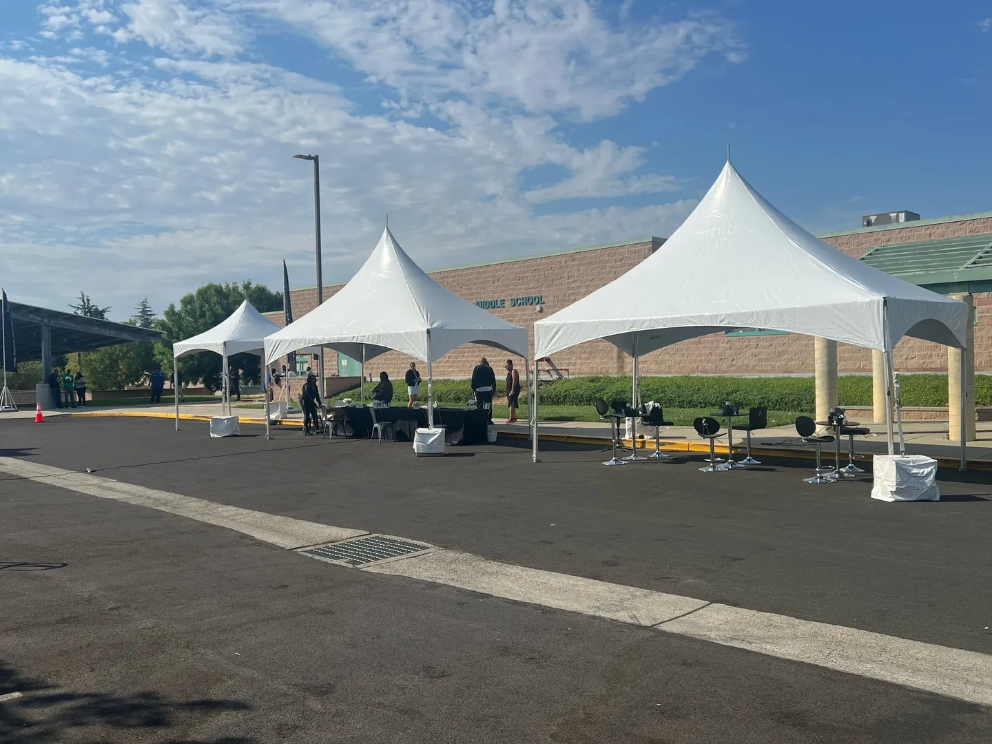 A group of people standing around tents on the side of a road.