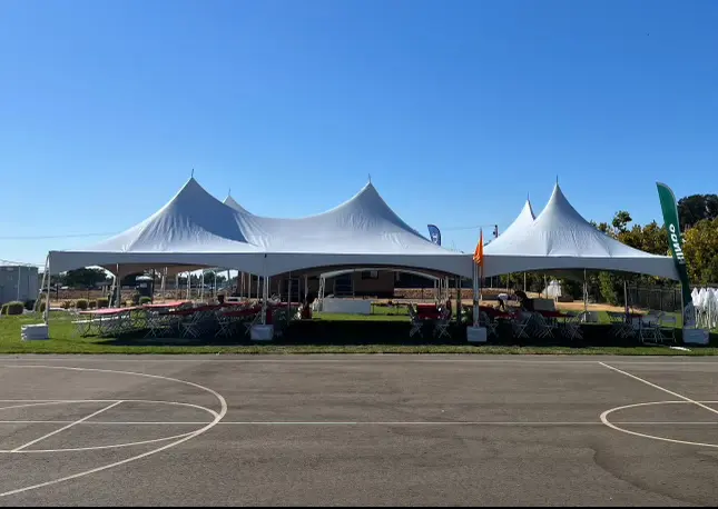 A large white tent is in the middle of an empty parking lot.